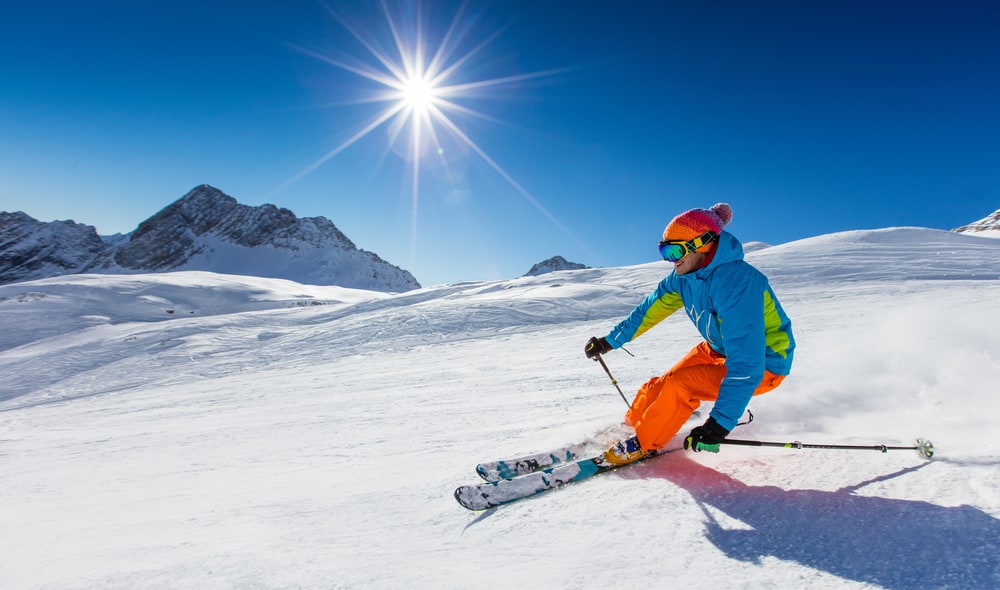 Skier on the slope and the sun in the background